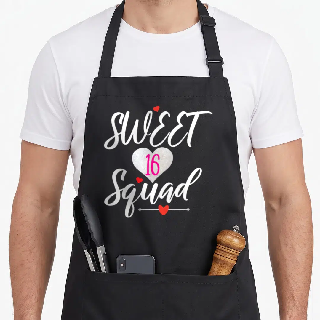 Sixteen youth birthday apron - SWEET 16 Squad text with silver glitter heart and small red hearts on white script — shown on a black cotton canvas apron against a white background