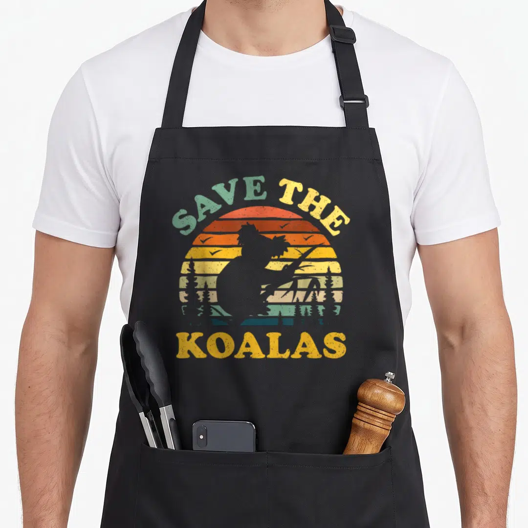Koala animal apron - Retro striped sun with koala silhouette and Save the Koalas text in yellow and orange — shown on a black cotton canvas apron against a white background