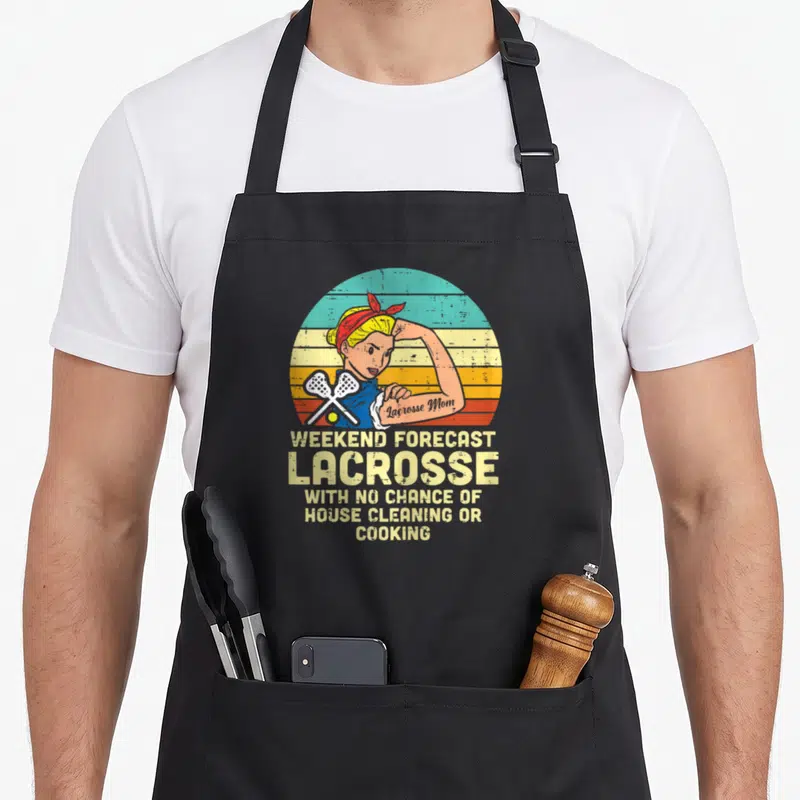Strong mama apron - Retro woman flexing with crossed lacrosse sticks and forecast text on striped background — shown on a black cotton canvas apron against a white background