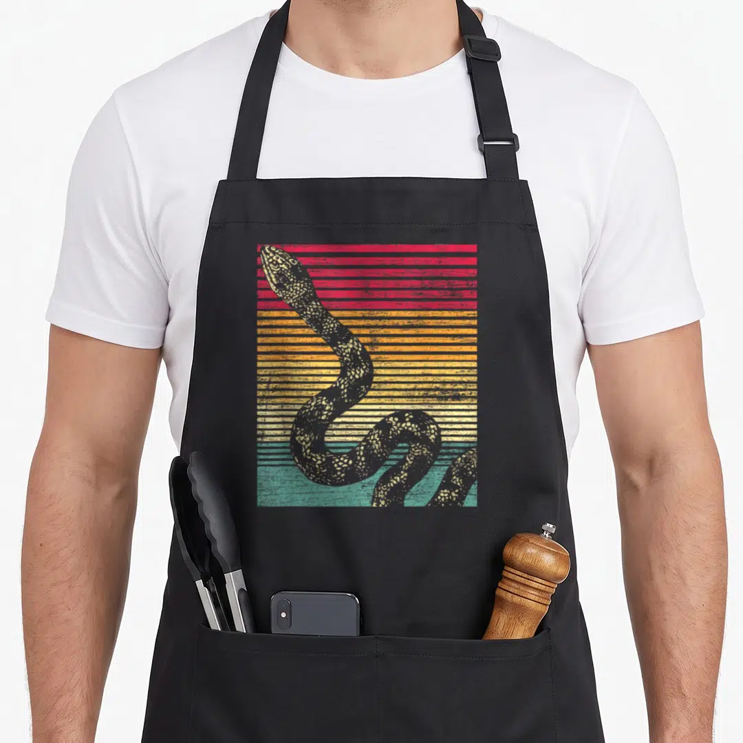 Funny snake lover apron - Grey coiled snake over retro red orange yellow and teal horizontal stripes — shown on a black cotton canvas apron against a white background