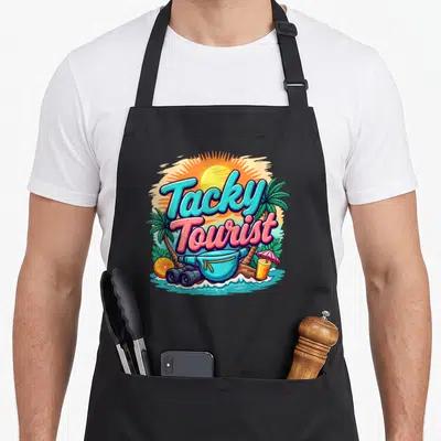 Vacay chef outfit with apron - Tacky Tourist text with fanny pack, binoculars, drink, and palm trees in cyan pink — shown on a black cotton canvas apron against a white background