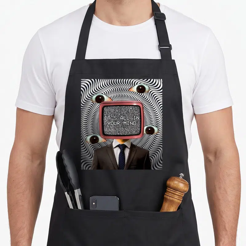Weirdcore weird aprons - TV headed man in suit with IT'S ALL IN YOUR MIND text and four floating eyes on spiral — shown on a black cotton canvas apron against a white background