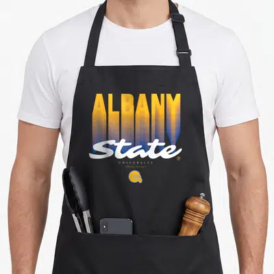 State essential apron - Stacked ALBANY text fading yellow to blue with white State script and small ram head logo below — shown on a black cotton canvas apron against a white background