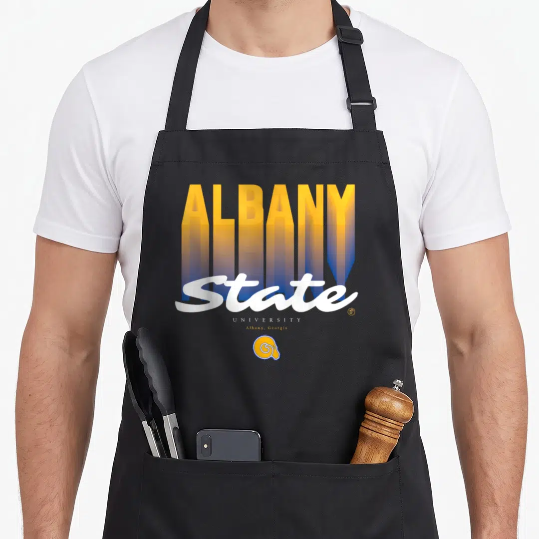 State essential apron - Stacked ALBANY text fading yellow to blue with white State script and small ram head logo below — shown on a black cotton canvas apron against a white background