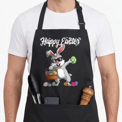 Dabbing easter bunny aprons - Grey cartoon bunny with sunglasses dabbing while holding a basket of colorful eggs — shown on a black cotton canvas apron against a white background