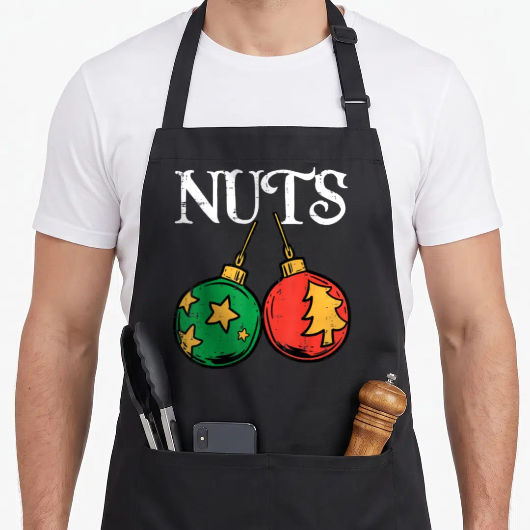 Xmas couples christmas aprons - NUTS text above green star and red tree Christmas ornaments — shown on a black cotton canvas apron against a white background