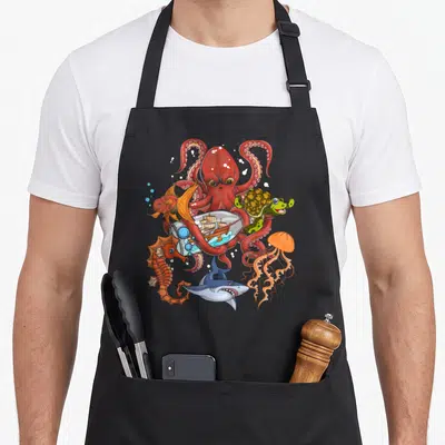 Jellyfish animal apron - Red cartoon octopus, blue shark, orange jellyfish, ship in bottle, green turtle, and seahorse — shown on a black cotton canvas apron against a white background