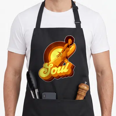 Funk 70s apron - Retro woman dancing over yellow orange brown sunburst with Soul 3D script text — shown on a black cotton canvas apron against a white background