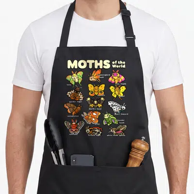 Moth animal apron - Cartoon grid of 15 moths including luna, rosy maple, and atlas with species names printed below each — shown on a black cotton canvas apron against a white background
