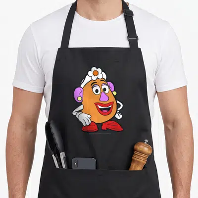 Portrait mrs apron - Cartoon Mrs. Potato Head with orange body, purple nose, red shoes, white gloves, and flower hat — shown on a black cotton canvas apron against a white background