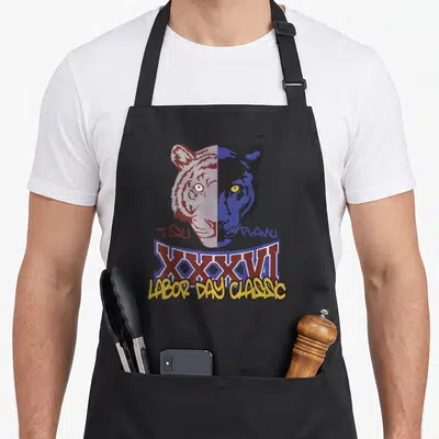 Tsu alumni apron - Split big cat head TDU PLANU XXXVI Labor Day Classic maroon blue yellow — shown on a black cotton canvas apron against a white background