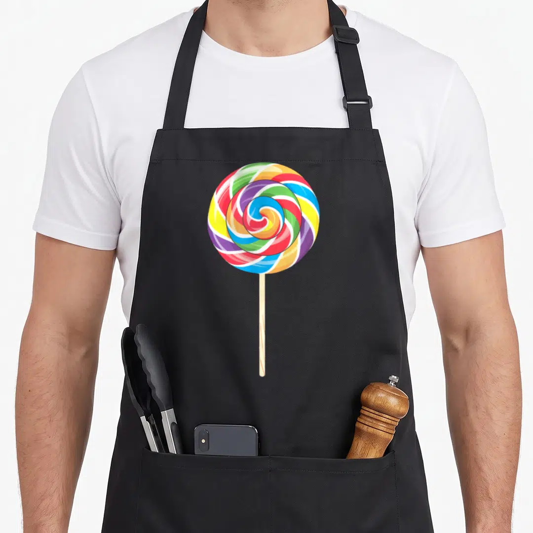 Lollipop rainbow apron - Multicolored spiral lollipop with red yellow green blue purple swirls and beige stick — shown on a black cotton canvas apron against a white background