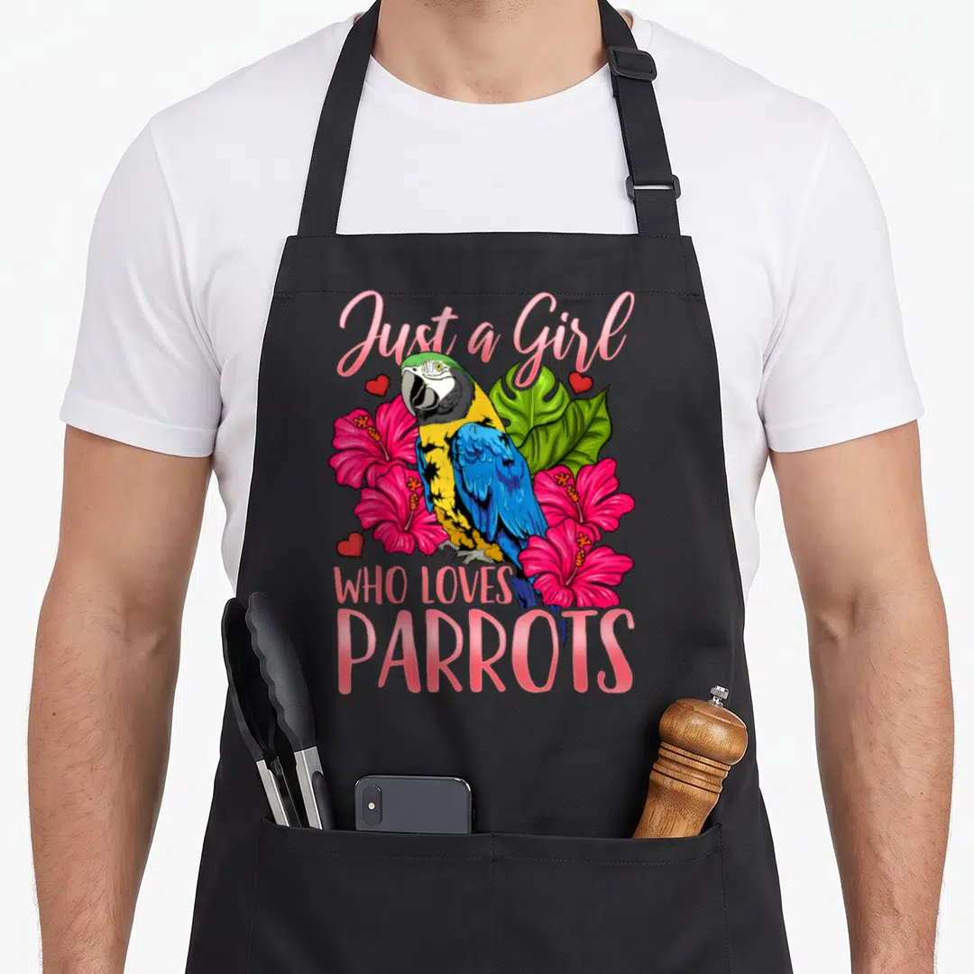 Parrot watching bird apron - Cartoon parrot with pink hibiscus flowers and text Just a Girl Who Loves Parrots — shown on a black cotton canvas apron against a white background