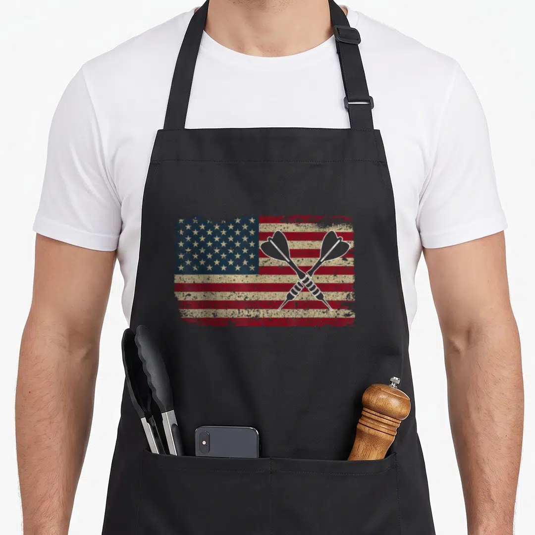 Dart american flag apron - Two crossed darts over a distressed red white and blue USA flag — shown on a black cotton canvas apron against a white background