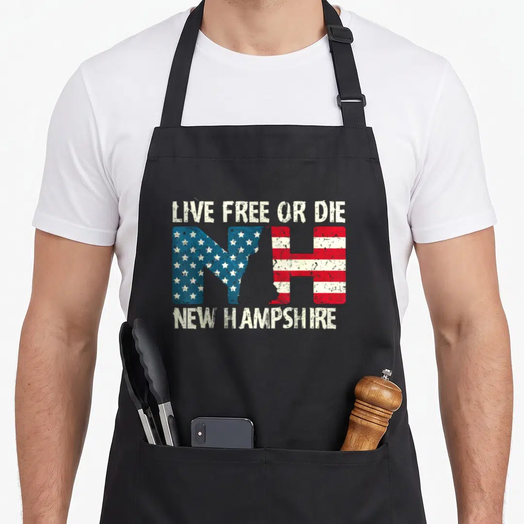 Hampshire patriotic apron - LIVE FREE OR DIE NH letters with US flag pattern and NEW HAMPSHIRE text in distressed white — shown on a black cotton canvas apron against a white background