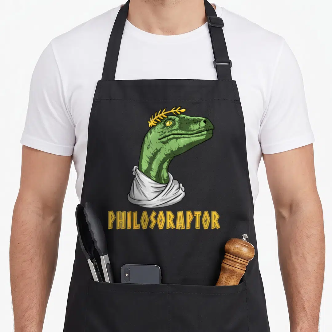 Philosophy major apron - Green raptor head wearing white toga and yellow laurel wreath above yellow text PHILOSORAPTOR — shown on a black cotton canvas apron against a white background