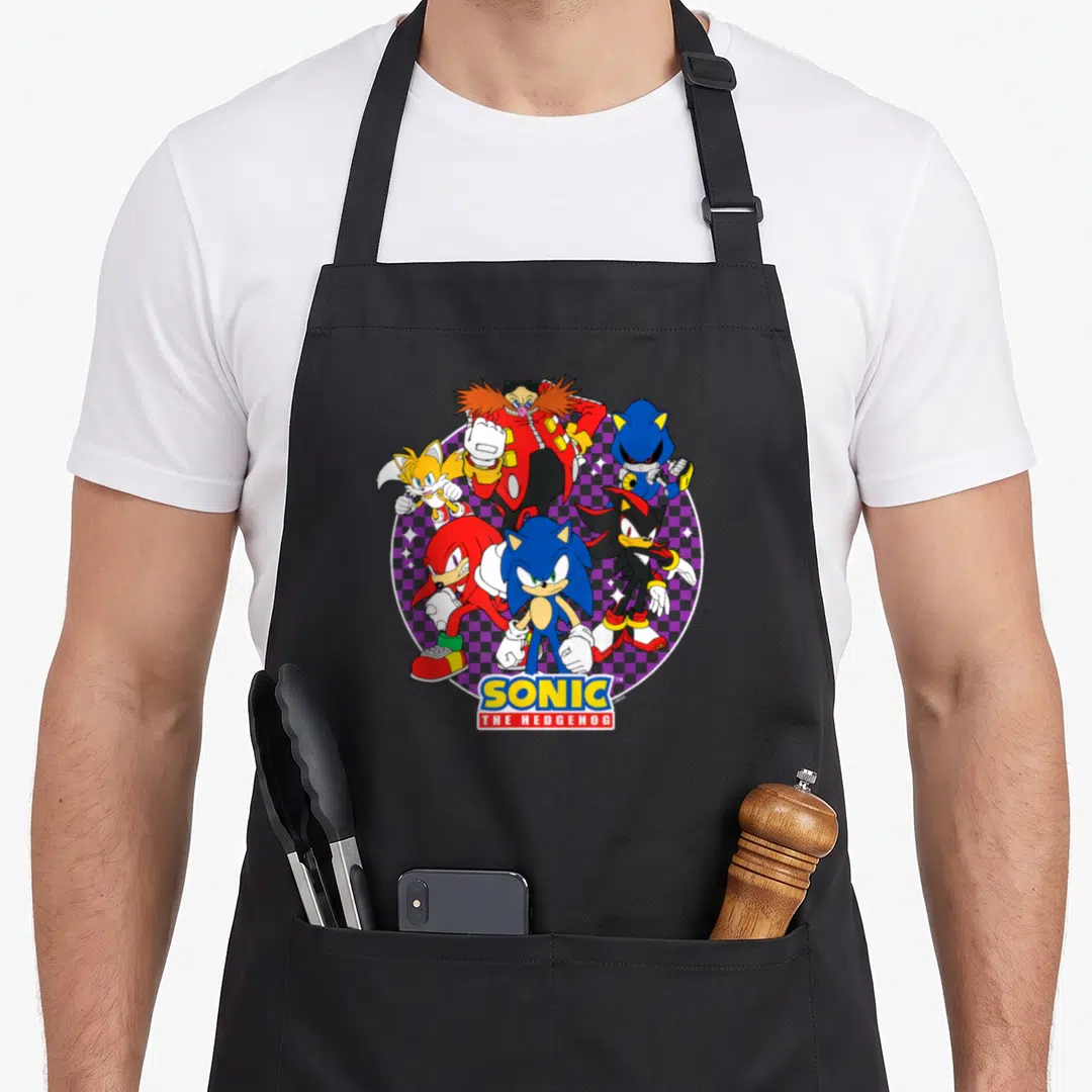 Heroe crazy hedgehog man apron - Sonic characters clustered over purple checkerboard circle with SONIC THE HEDGEHOG logo — shown on a black cotton canvas apron against a white background