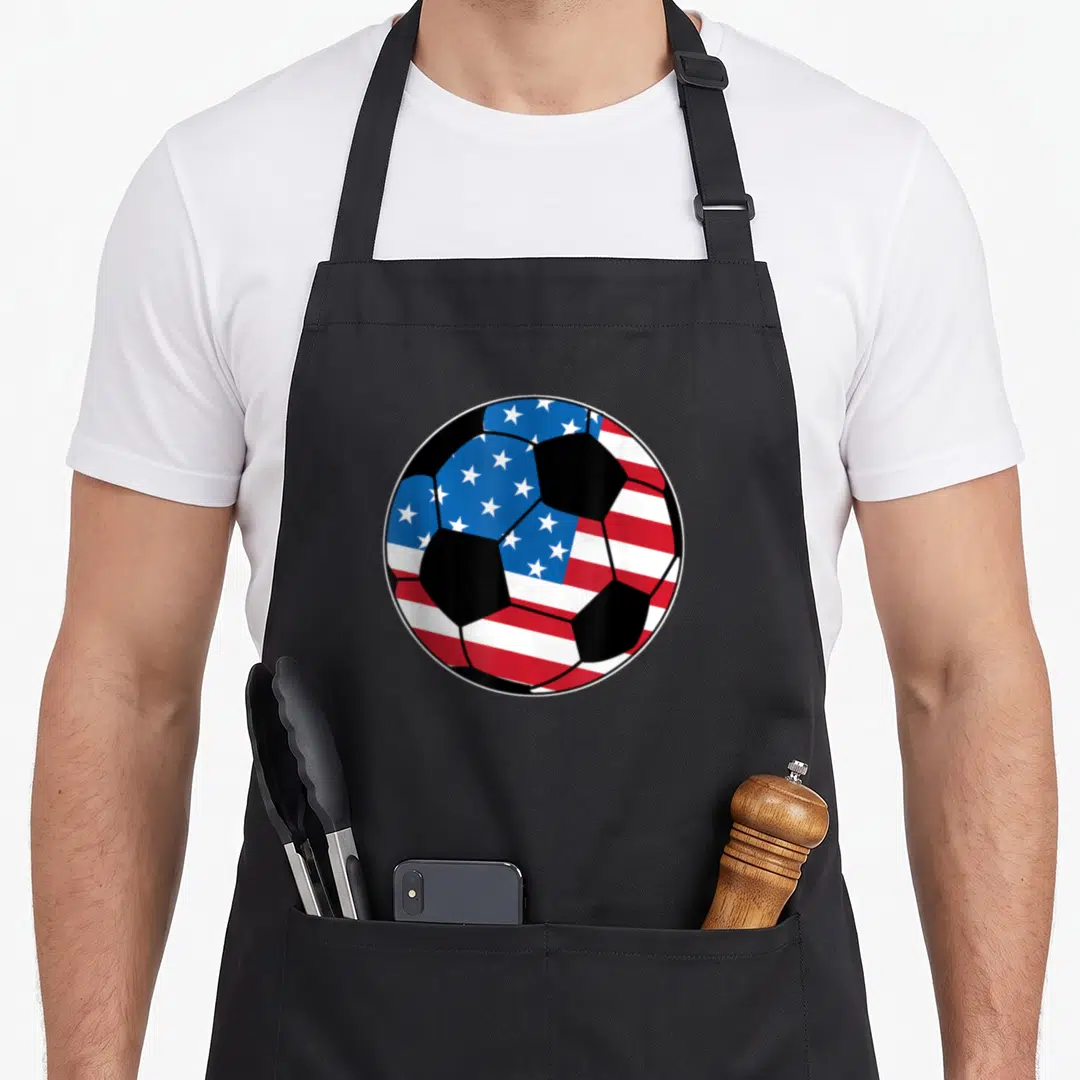 State stripe apron - Soccer ball with US flag pattern in red white blue and black — shown on a black cotton canvas apron against a white background