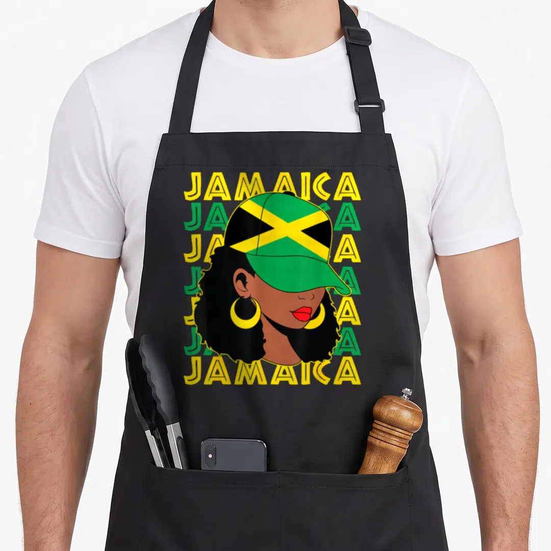 Afro pride apron - Woman with afro and Jamaica flag cap over five stacked Jamaica text lines in green yellow and black — shown on a black cotton canvas apron against a white background