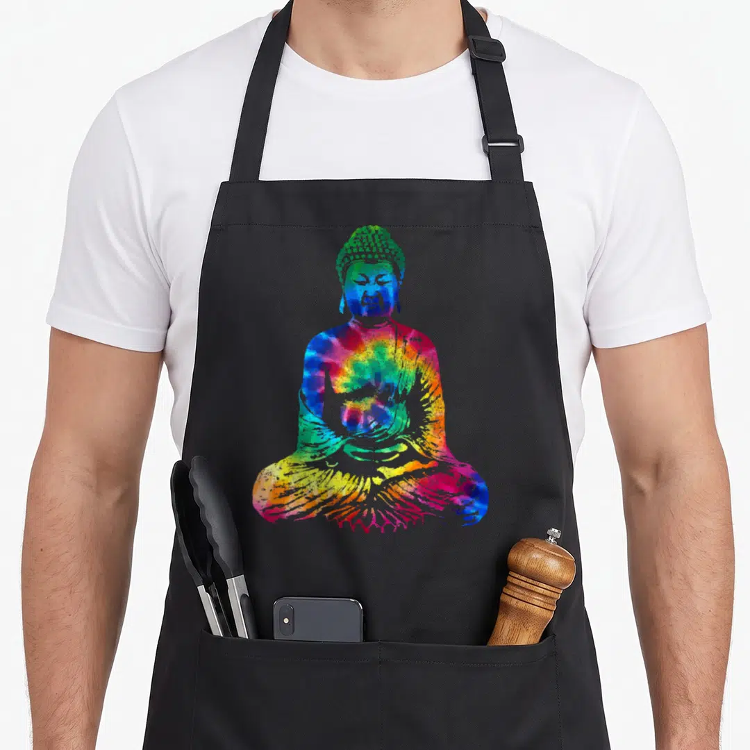 Buddha tie-dye apron - Seated Buddha silhouette filled with blue, green, yellow, red, and purple tie-dye pattern — shown on a black cotton canvas apron against a white background