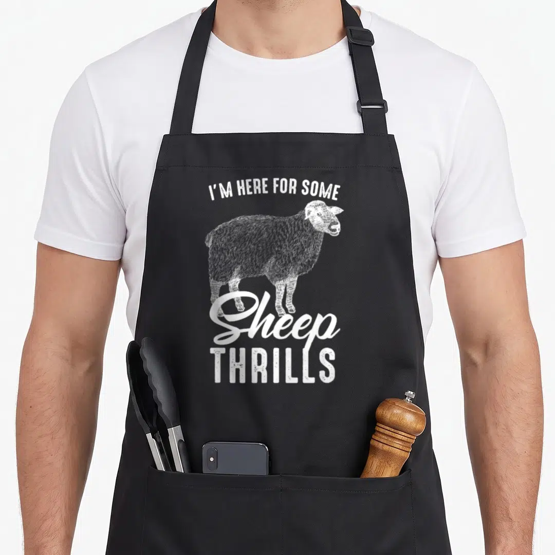 Sarcasm sheep apron - White distressed sheep illustration with text I'm Here For Some Sheep Thrils — shown on a black cotton canvas apron against a white background