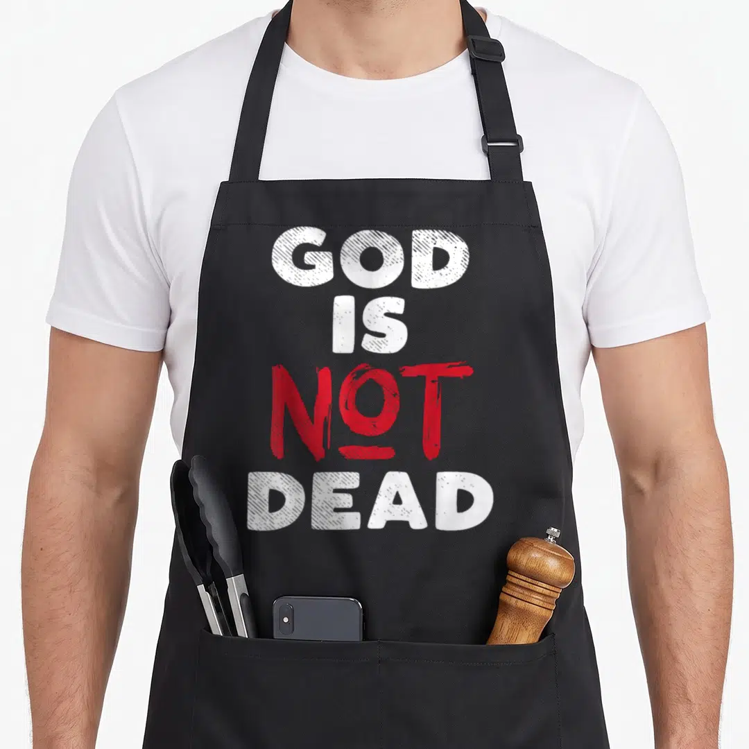 Boredkoalas christian apron - Stacked white and red text reading GOD IS NOT DEAD — shown on a black cotton canvas apron against a white background