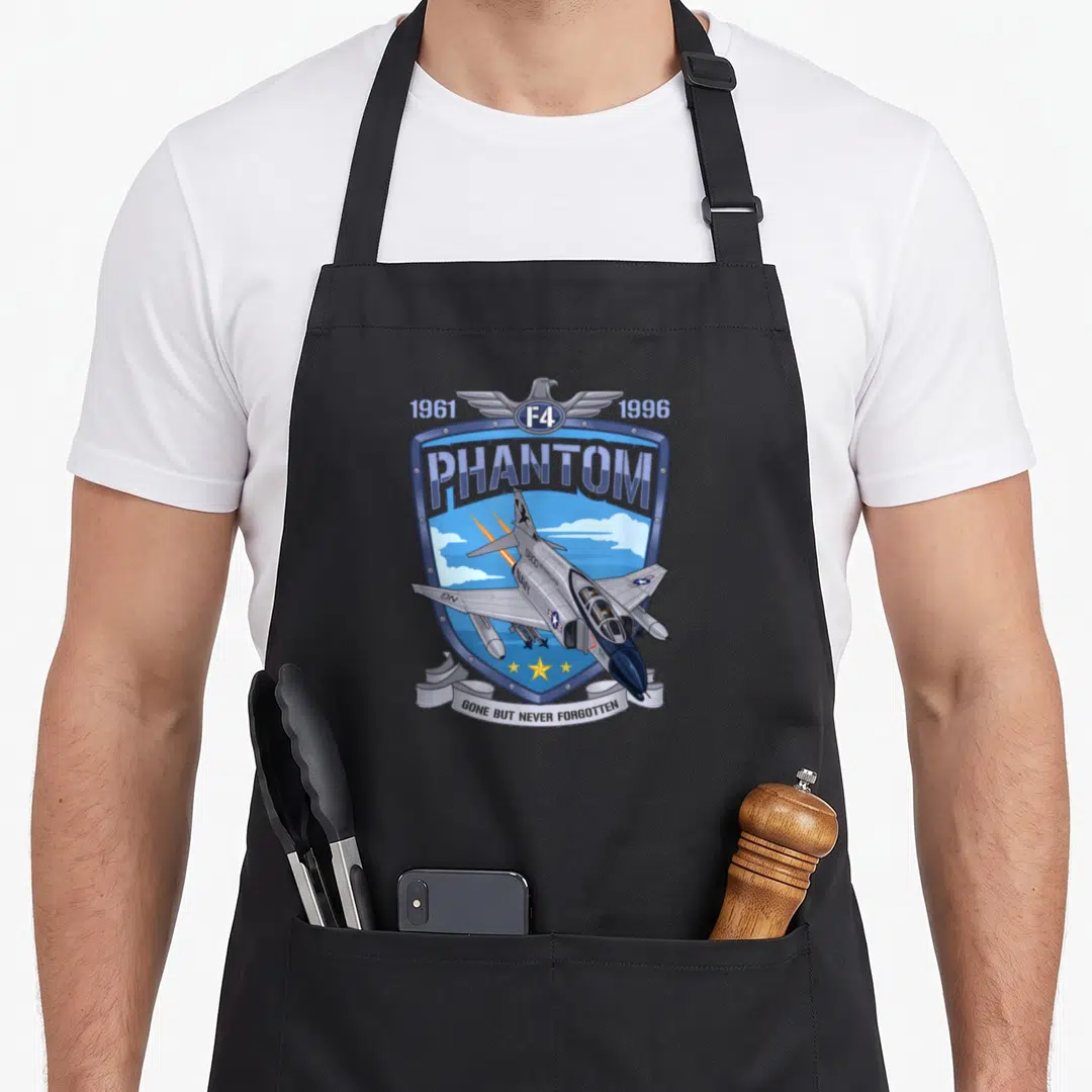 Phantom aviation apron - F4 Phantom jet in blue shield with eagle, 1961 1996 dates, and Gone But Never Forgotten banner — shown on a black cotton canvas apron against a white background