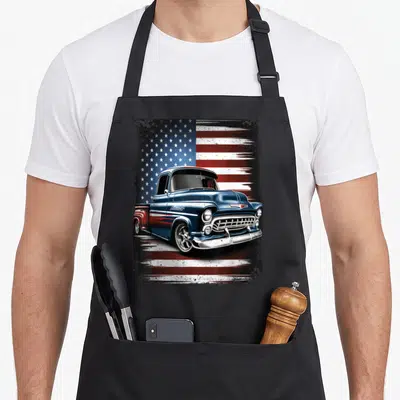 Pickup 4th of july apron - Blue vintage truck illustration on distressed American flag background — shown on a black cotton canvas apron against a white background