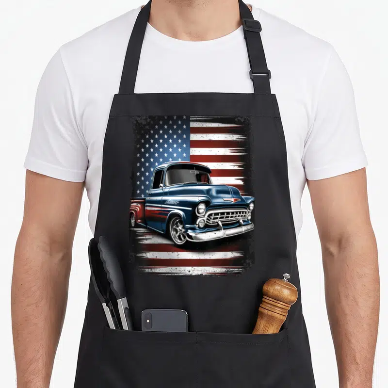 Pickup 4th of july apron - Blue vintage truck illustration on distressed American flag background — shown on a black cotton canvas apron against a white background