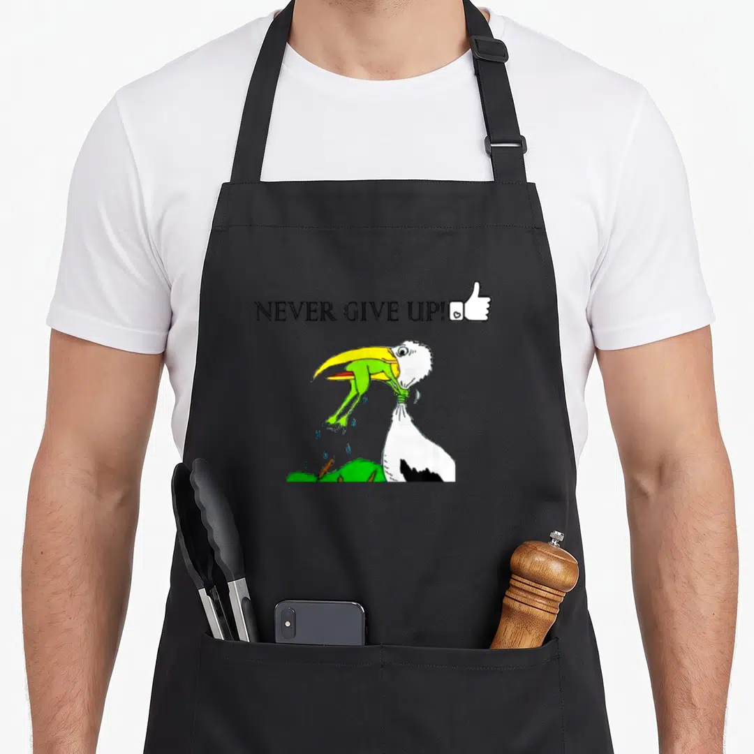 Motivational dont give apron - Cartoon toucan with yellow beak holding green frog, noose around neck, text NEVER GIVE — shown on a black cotton canvas apron against a white background