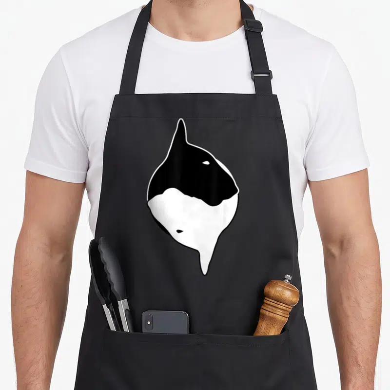 Yin dog dad apron - Stylized black and white orca shape resembling a yin yang symbol — shown on a black cotton canvas apron against a white background