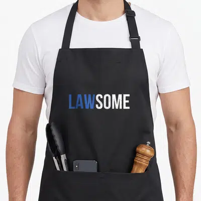 Law exam apron - LAWSOME text in blue and white sans-serif font on grey background — shown on a black cotton canvas apron against a white background