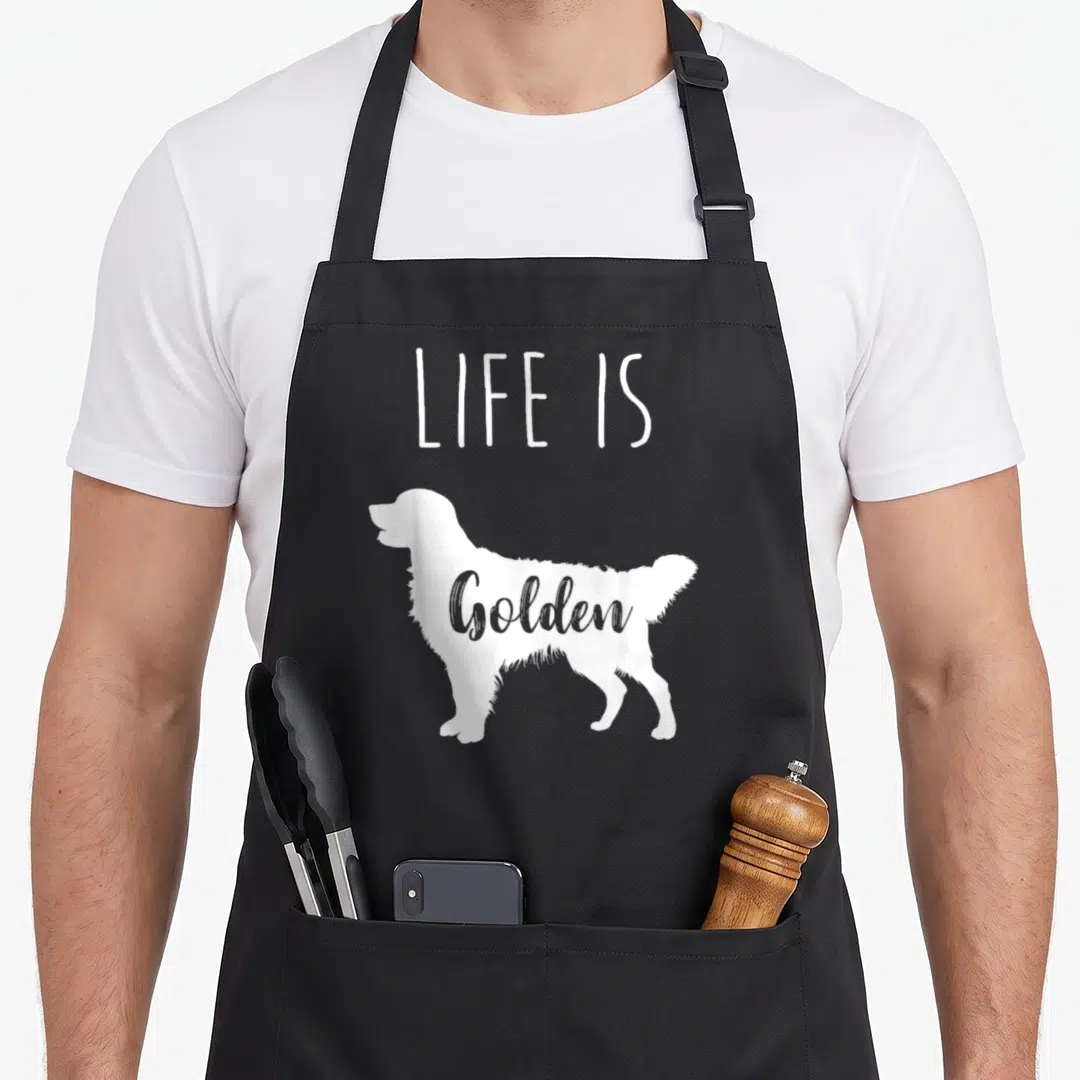 Vintage golden retriever apron - White dog silhouette with LIFE IS above and Golden inside on black background — shown on a black cotton canvas apron against a white background