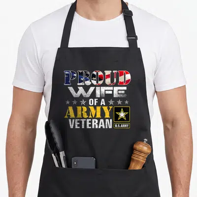Wife american flag apron - Stacked text PROUD WIFE OF A ARMY VETERAN with flag pattern fill and U.S.Army logo block — shown on a black cotton canvas apron against a white background