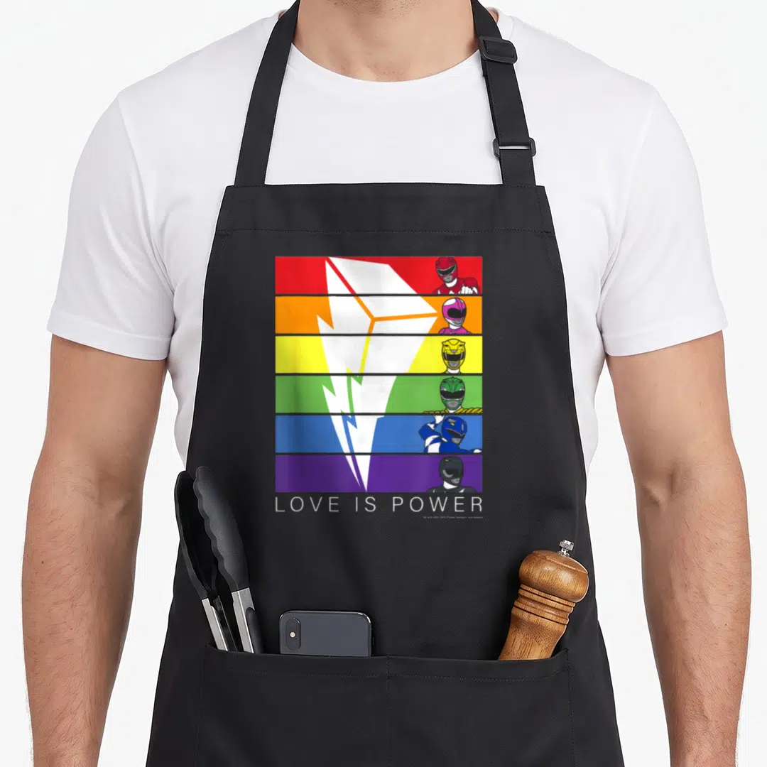 Panel rainbow apron - Six rainbow stripes with Power Rangers and white lightning bolt above LOVE IS POWER text — shown on a black cotton canvas apron against a white background