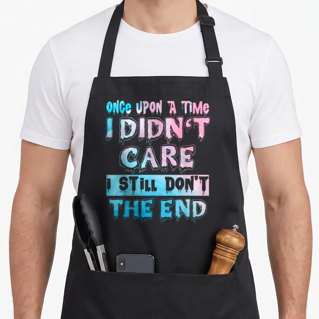 Goth snarky aprons - Dripping blue and pink text reading ONCE UPON A TIME I DIDN'T CARE I STILL DON'T THE END on grey — shown on a black cotton canvas apron against a white background