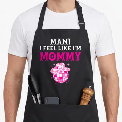 Feel birthday cowgirl aprons - Pink and white disco ball in a cowboy hat below stacked mommy text — shown on a black cotton canvas apron against a white background