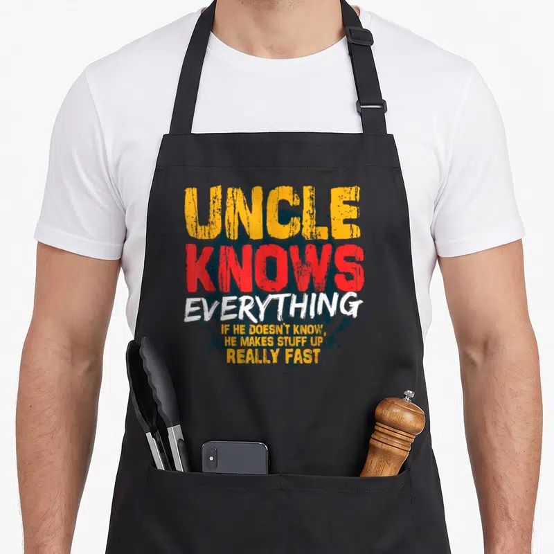 Cute uncle father day apron - Stacked distressed text in yellow red and white over a dark blue circle reading Uncle — shown on a black cotton canvas apron against a white background