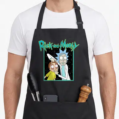 Space cartoon apron - Rick and Morty title text above Rick pulling open Morty's eyes against a starry black background — shown on a black cotton canvas apron against a white background