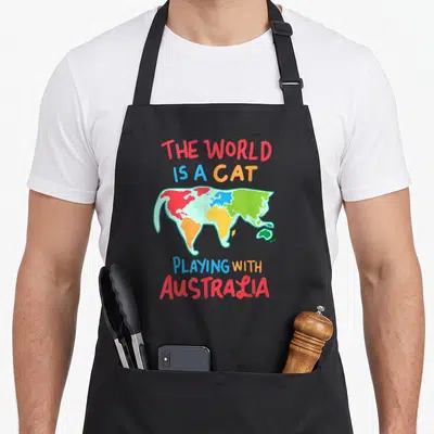Playing australia cute cat apron - Cartoon cat world map with colored continents and text playing with Australia — shown on a black cotton canvas apron against a white background