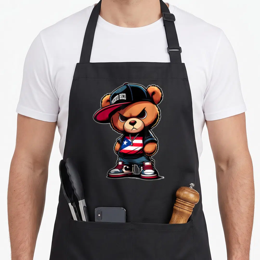 Puerto teddy bear apron - Cartoon brown bear wearing a cap with PUERTO RICO text and a red white and blue flag shirt — shown on a black cotton canvas apron against a white background