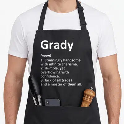Grady father day aprons - White text defining Grady as handsome, humble, and a jack of all trades on a grey background — shown on a black cotton canvas apron against a white background