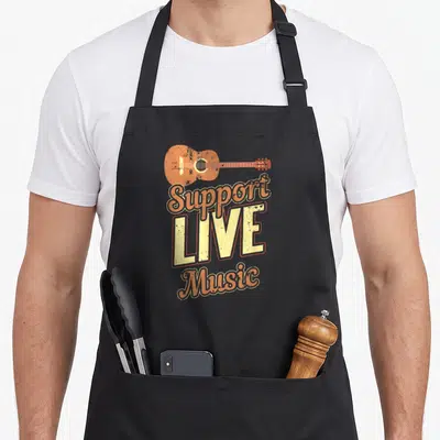 Support indie rock apron - Acoustic guitar above orange and yellow text reading Support LIVE Music in retro style — shown on a black cotton canvas apron against a white background