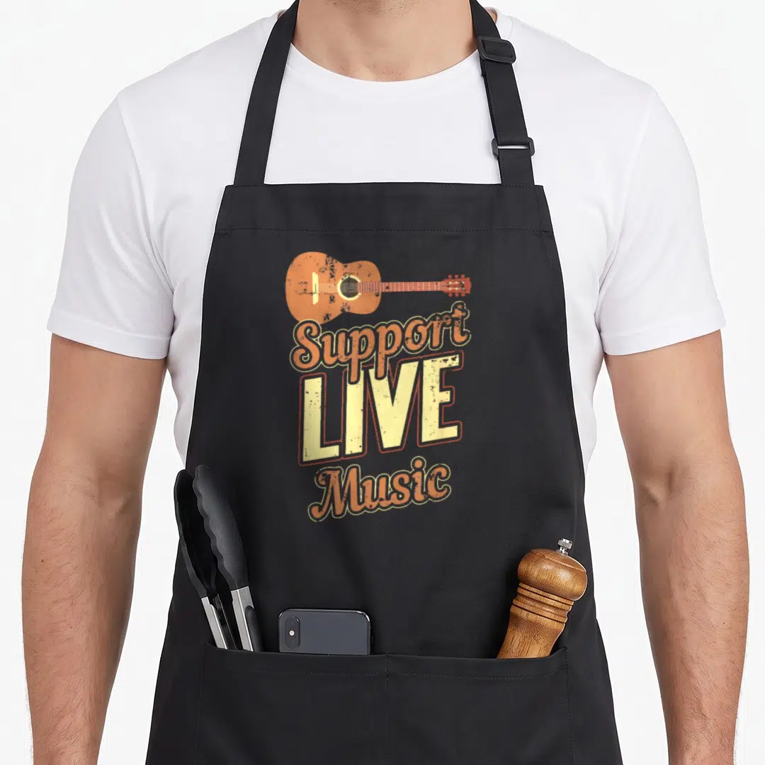 Support indie rock apron - Acoustic guitar above orange and yellow text reading Support LIVE Music in retro style — shown on a black cotton canvas apron against a white background