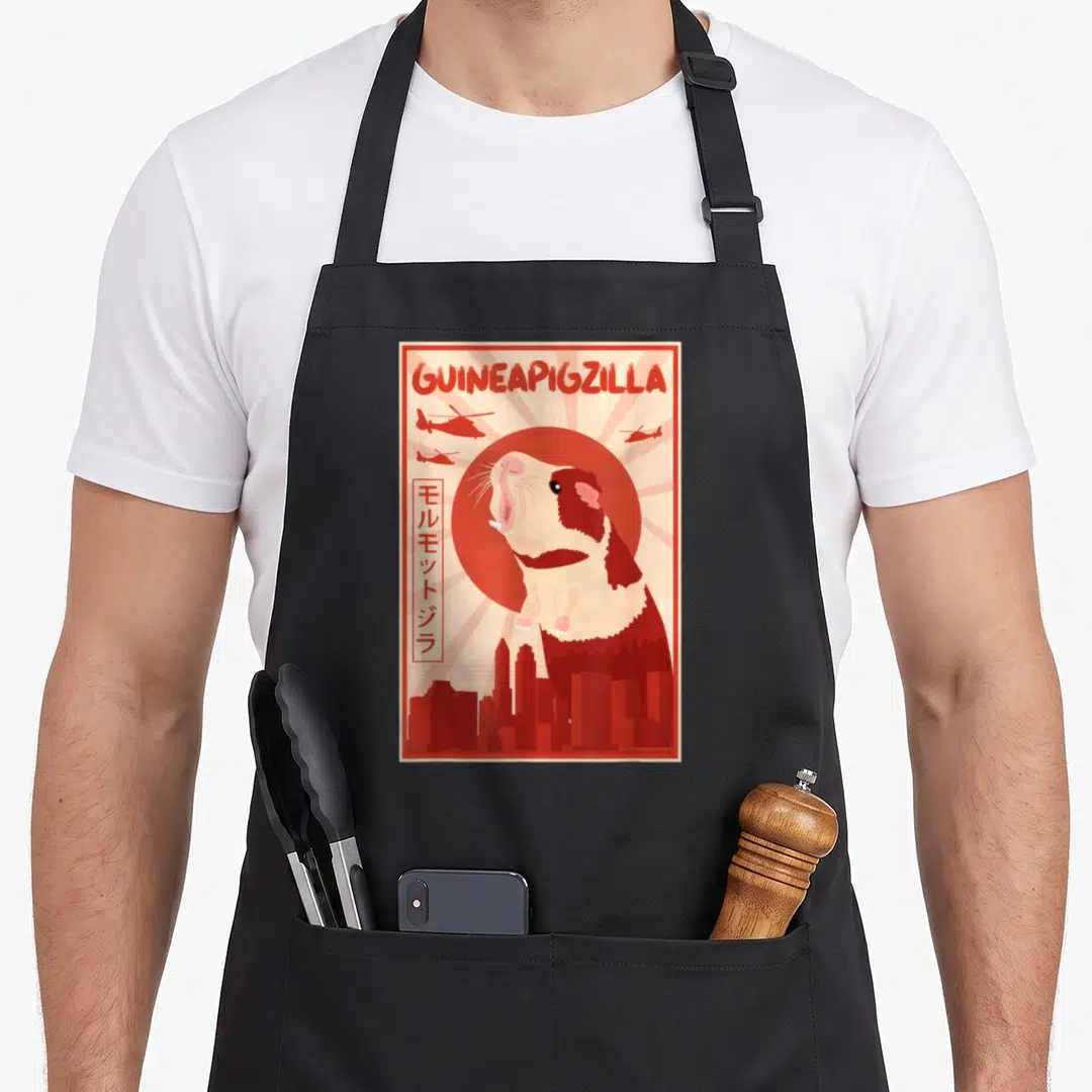 Accessory crazy guinea man apron - Retro red and cream giant guinea pig with helicopters and Japanese text over city — shown on a black cotton canvas apron against a white background