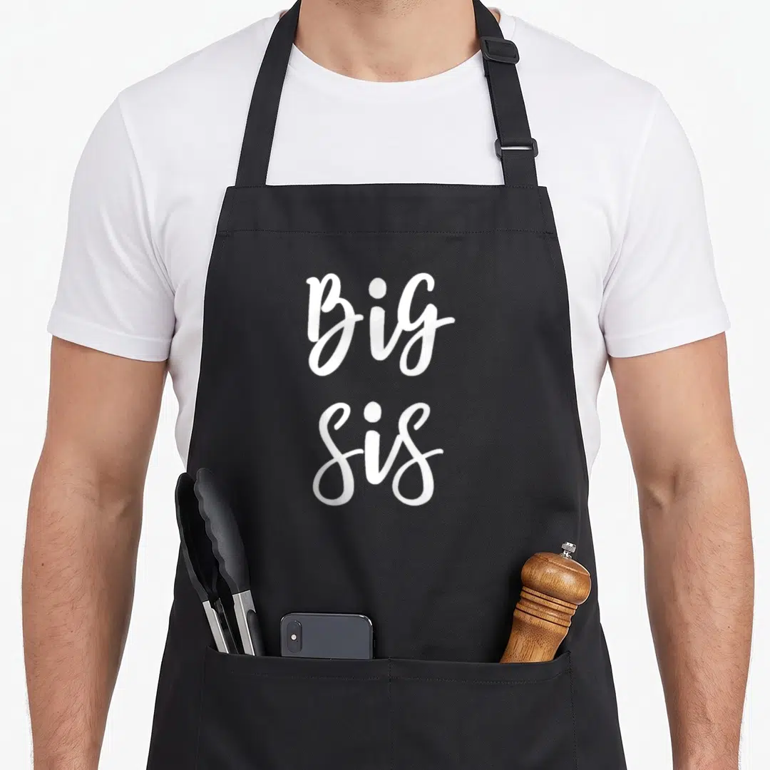 Sis family aprons - White Big Sis script text stacked vertically on a dark background — shown on a black cotton canvas apron against a white background