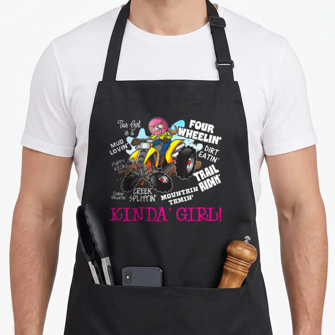 Four road apron - Cartoon girl on yellow ATV surrounded by mud lovin four wheelin trail ridin text — shown on a black cotton canvas apron against a white background