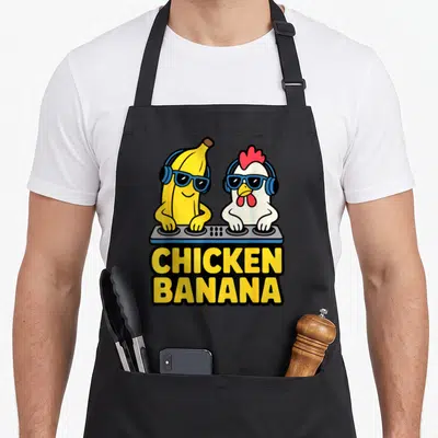 Chicken banana apron - Cartoon yellow banana and white chicken wearing blue sunglasses behind a grey DJ controller — shown on a black cotton canvas apron against a white background