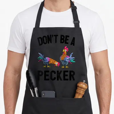 Pecker hen apron - Two cartoon roosters with DON'T BE A PECKER text in black blue orange and red — shown on a black cotton canvas apron against a white background