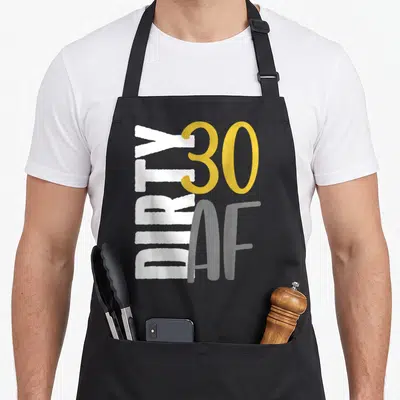 Thirtieth funny dirty aprons - Vertical white DIRTY, large yellow 30, and grey AF text in distressed style — shown on a black cotton canvas apron against a white background